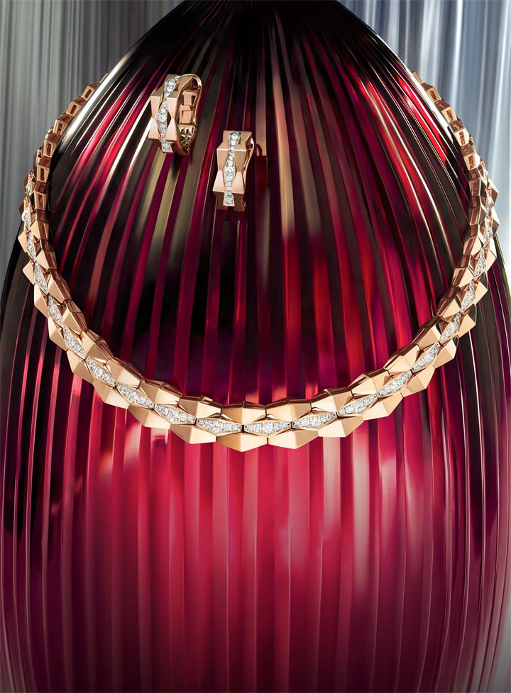Gold chain necklace and earrings on a red fluted glass backdrop